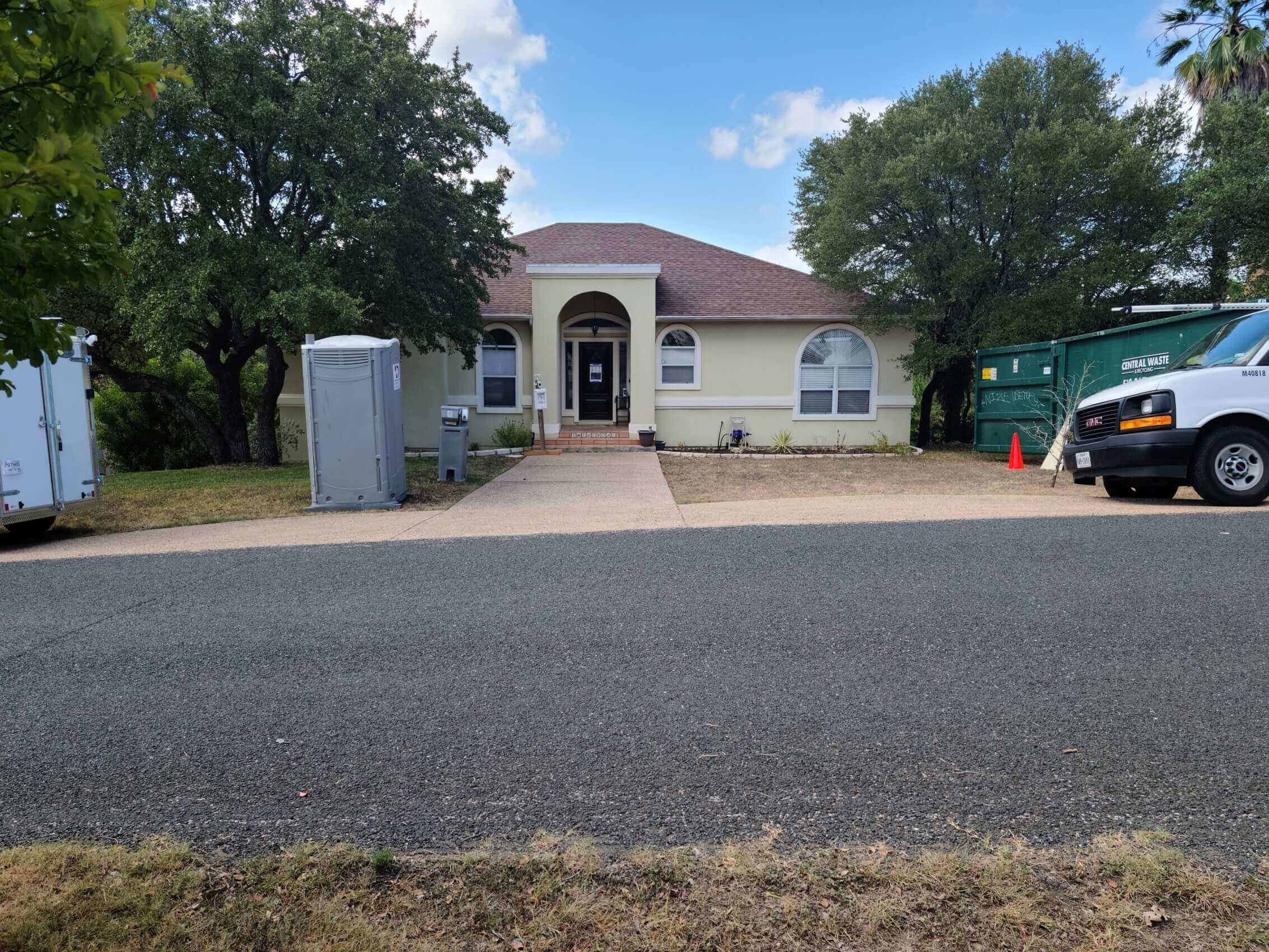 House being remodeled with a dumpster out front and some work trucks