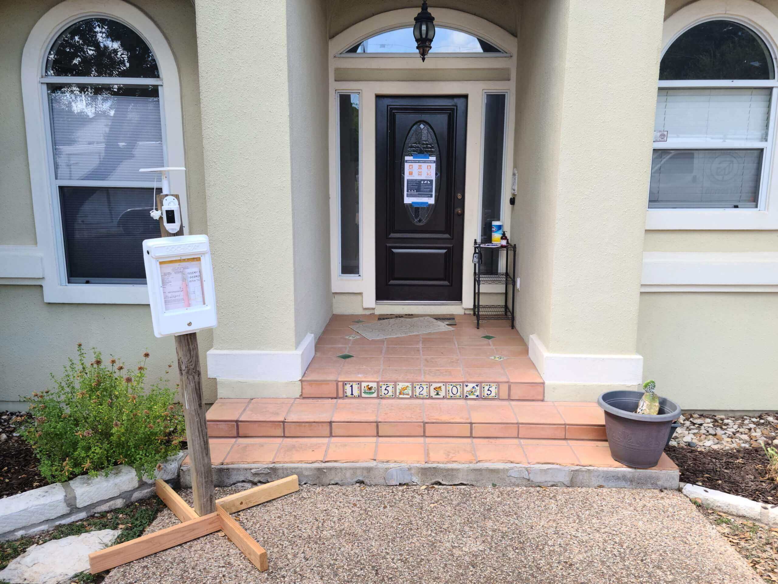 Front entrance of a home being remodeled with a sign-in sheet for safety measures