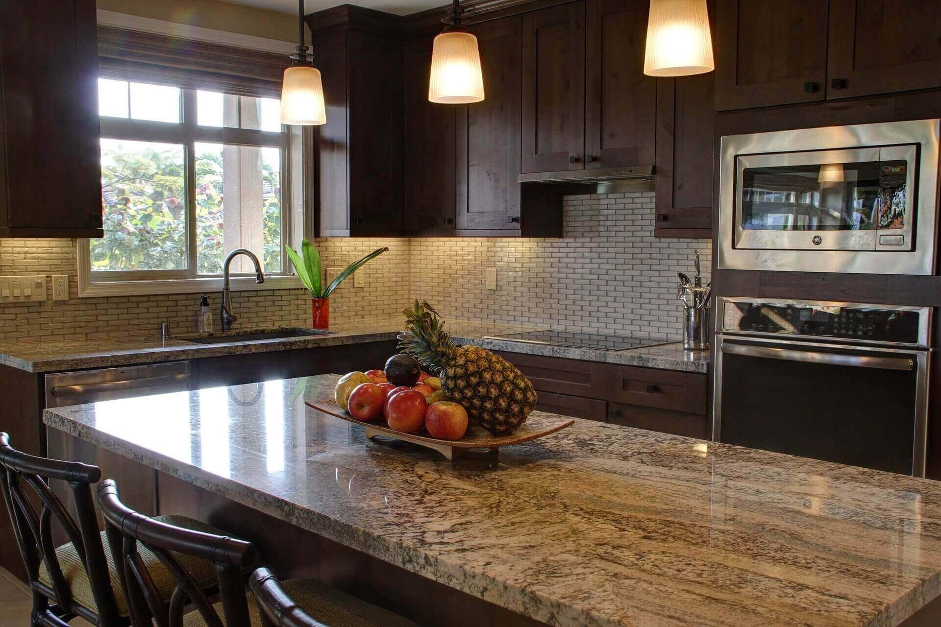 Modern Kitchen with dark brown cabinets, a large marble top island, and stainless steel appliances