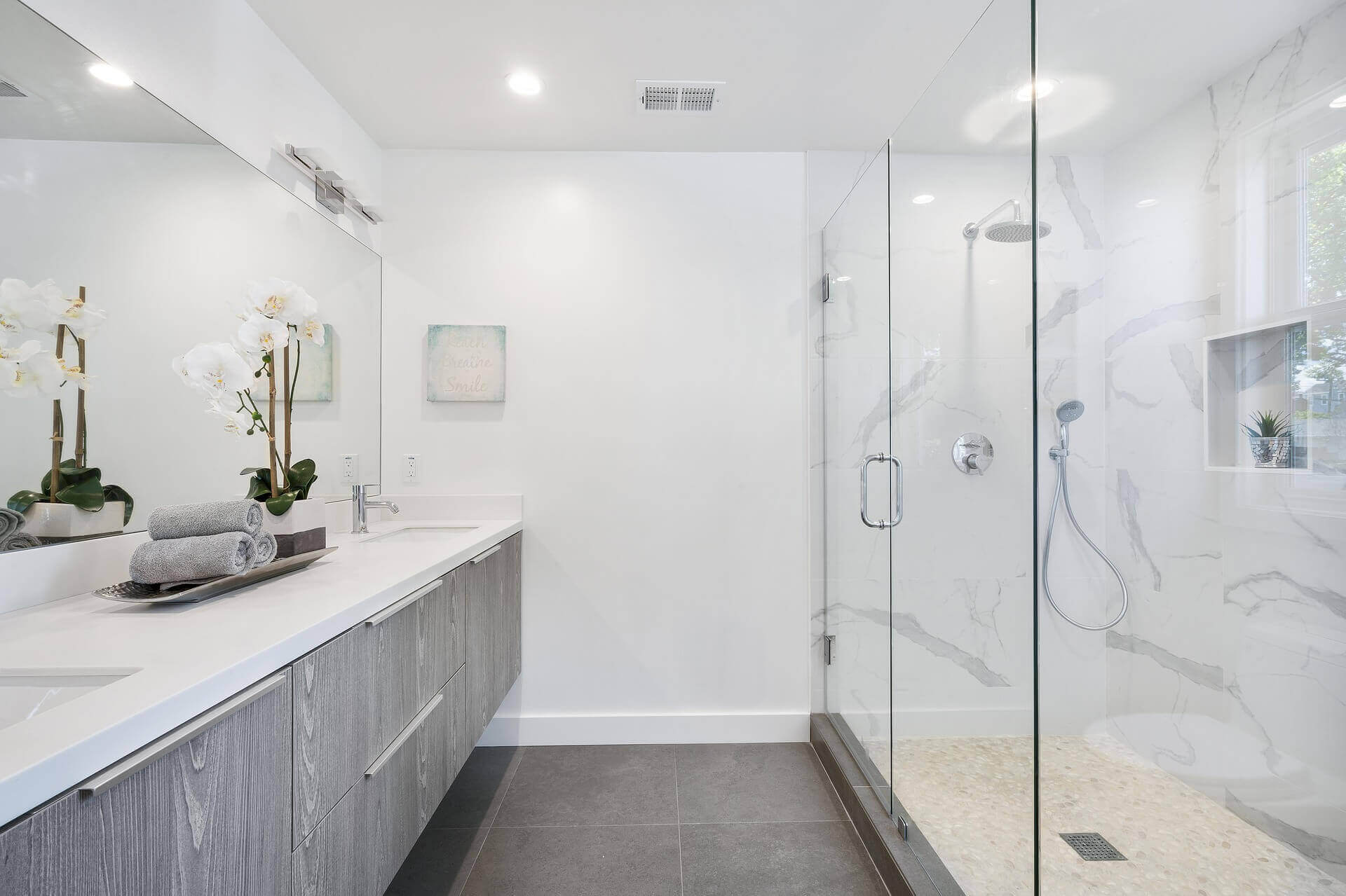 Bathroom with zero edge shower, floating cabinets, and giant mirror