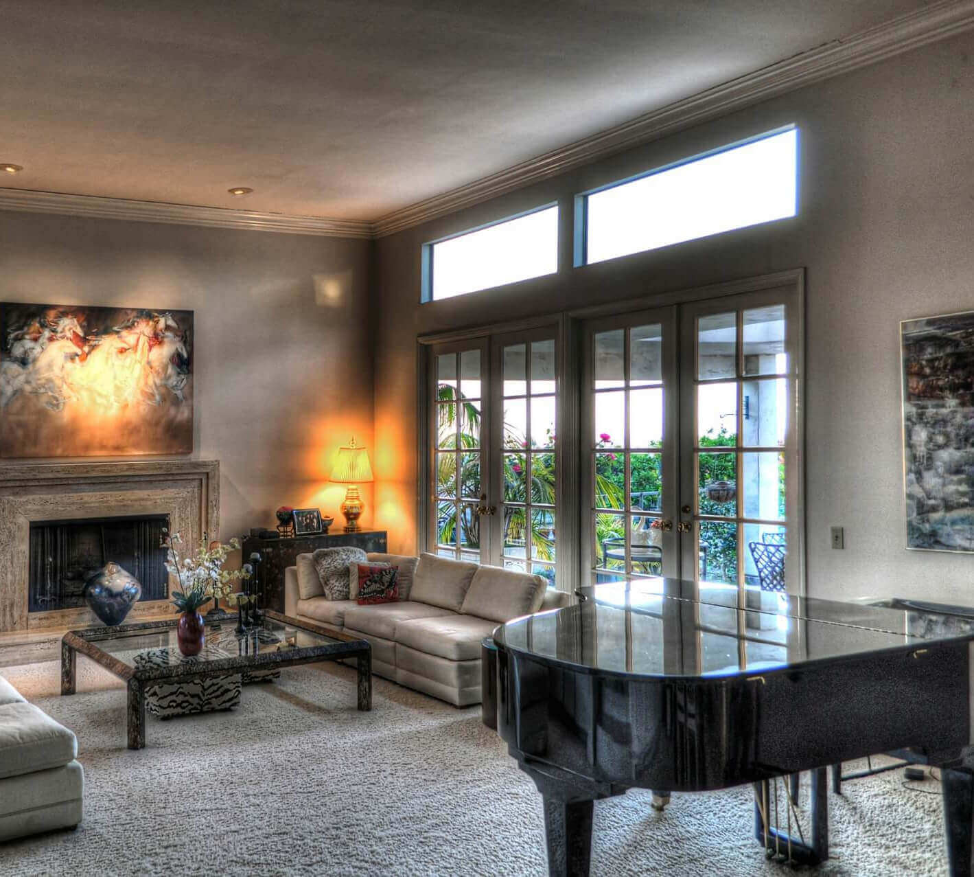 Custom home's Luxurious living-room with grand piano, fireplace, and large french doors.