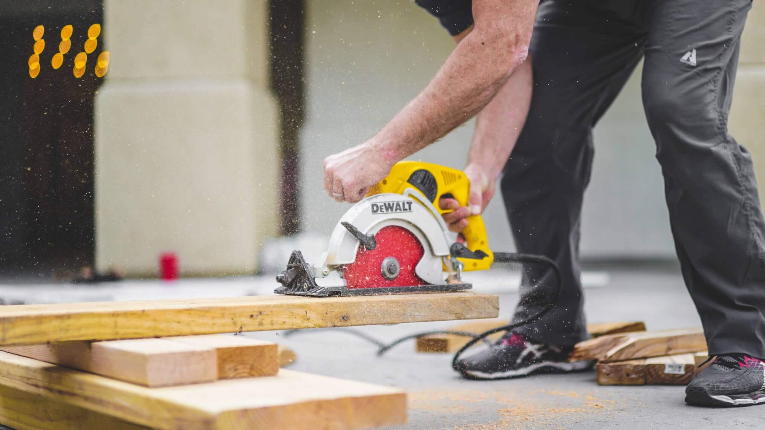 A man is cutting through a wooden plank with a saw.