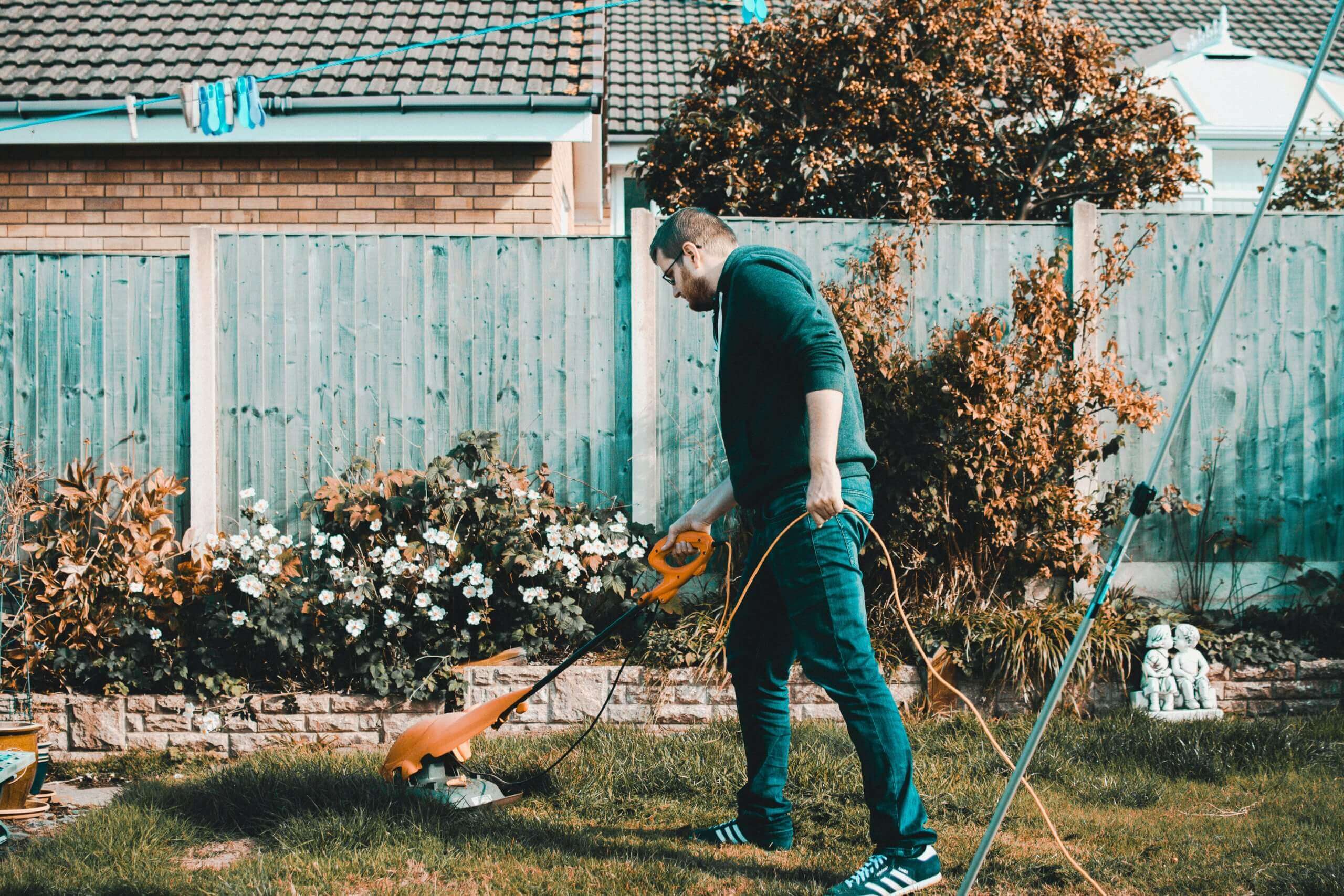 A man is mowing his lawn to improve the landscaping.